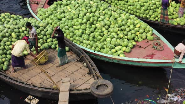 Aerial view of workers exchanging watermelons on boats along the Buriganga River.