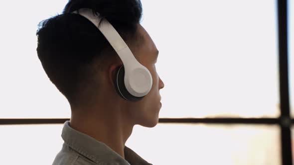 Young Asian Man in Headphones Listens to Music Nodding Head