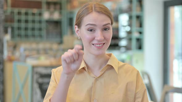 Portrait of Young Woman Pointing at Camera and Inviting 