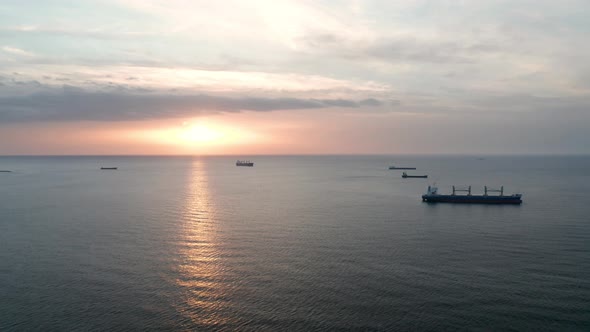 A drone flight around container ships into the sea at sunrise