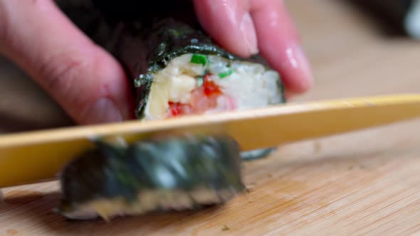 The Chef Cuts Sushi and Rolls Made From Seafood with Asian Ingredients with a Knife