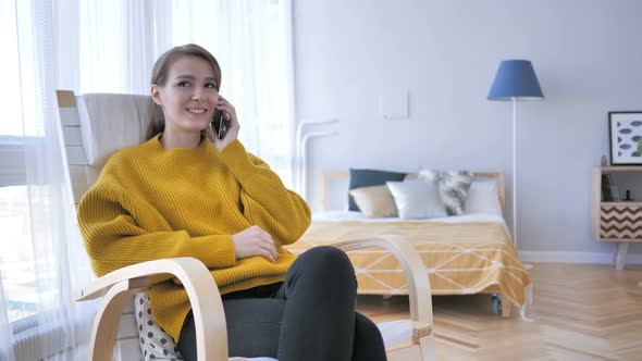 Young Woman Talking on Phone while Relaxing on Chair