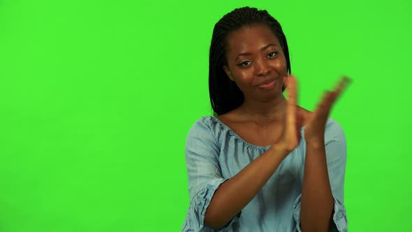 A Young Black Woman Smiles at the Camera and Applauds - Green Screen Studio