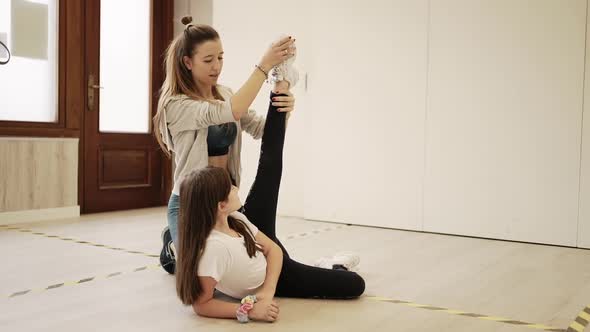 Dance instructor helping girl with stretching legs