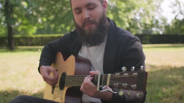 Man Playing Guitar in Park on Sunny Day