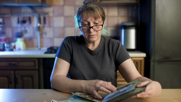 Middle aged woman looking at family photo album. Nostalgia, sadness