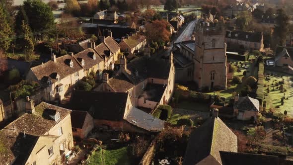 Aerial drone video of a Cotswolds Village Church, a rural scene in English countryside with houses, 