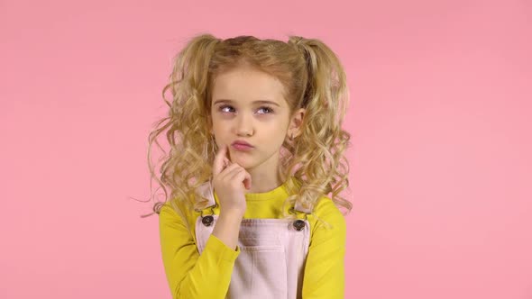 Blond Female with Two Ponytails Is Concentrated on Thinking, Touching Her Face with Finger