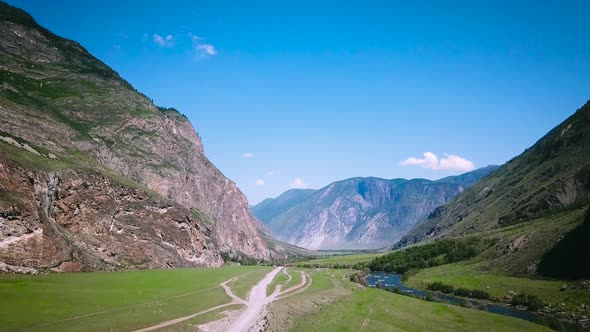 Aerial View From Above on the Country Road in Mountain Range in Between Green Grass Hills and Around