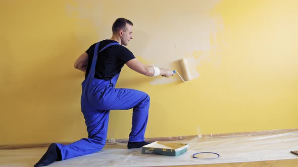 Young man painting wall with roller brush while renovating his apartment. Repair, building and home 