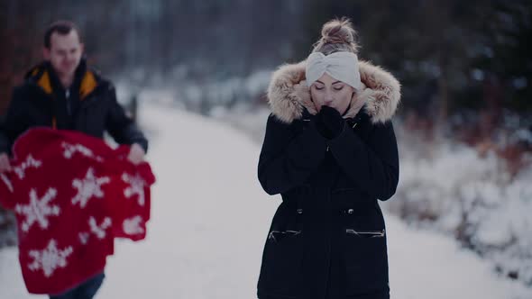 Woman Giving Hand To Boyfriend Ona Walk in Forest in Winter