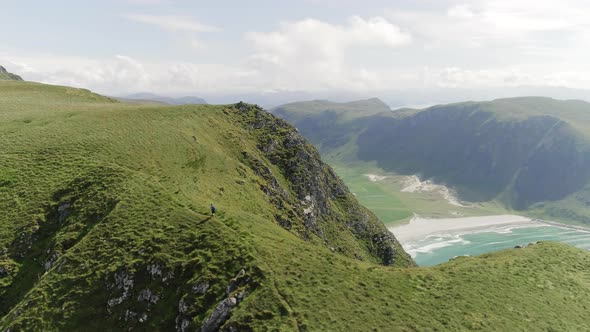 A Man Standing On Top of a Mountain Looking Down at the Beach