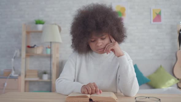 Portrait African American Woman with an Afro Hairstyle Reading a Book at the Table