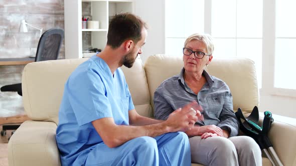 Male Doctor Assistant Sitting on the Couch with Senior Woman