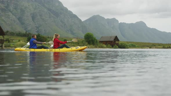 Caucasian couple having a good time on a trip to the mountains, kayaking together on a lake