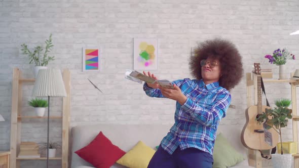 Portrait of a Happy African Woman with an Afro Hairstyle in Sunglasses Throwing Out Money Banknotes