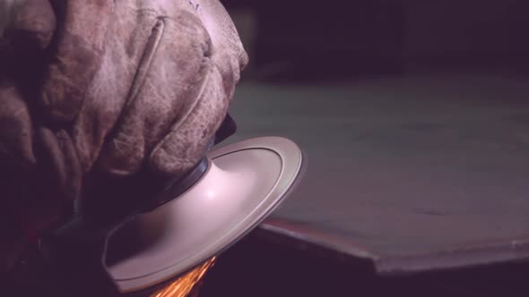 Crop metal worker in gloves grinding edge of metal handiwork