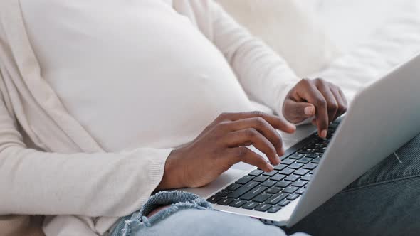 Closeup African Pregnant Woman Female Hands with Tummy Belly Typing on Keyboard Uses Laptop for