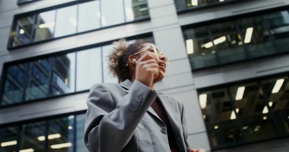 A Woman Wearing Headphones Listens to Music and Dances Outside Office Building