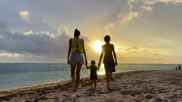 Happy Cheerful Family Walking on the Beach at a Beautiful Sunset