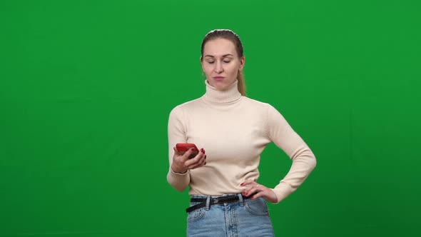 Young Woman with Dissatisfied Facial Expression Checking Smartphone at Chromakey Background