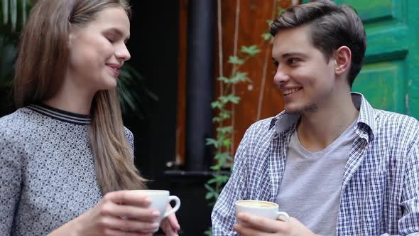 Couple In Cafe. Young People Drinking Coffee And Communicating