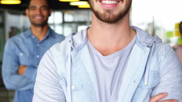 Portrait of happy male executives standing with arms crossed