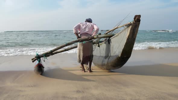 Man Pulls Traditional Hand Made Fishing Boat Against Sea