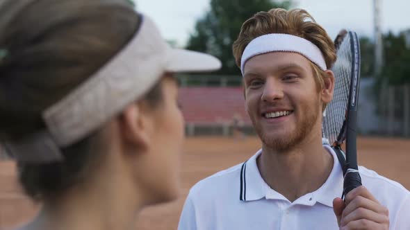 Female Flirting With Red Headed Tennis Player At Court, Man Smiling To Girl