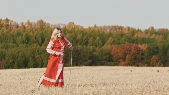 Feisty Woman in Red Dress Training on the Field - Trains with a Sword and Throws It Up