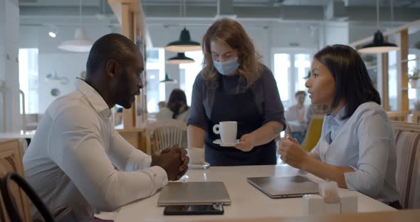 Side View of African Colleagues Discuss at Business Meeting in Cafe