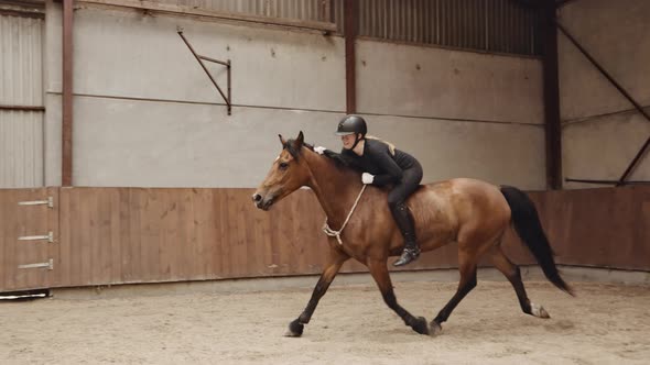 Tracking Wide Slow Motion Shot Of Young Woman Riding Horse Bareback In Paddock