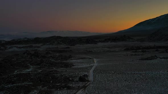 Cars Driving On Snowy Road In Alabama Hills, California At Sunset. wide aerial