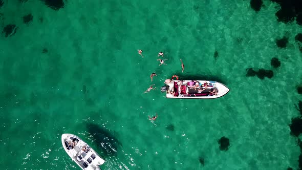 Bird's Eye View of Tourists Swimming in the Crystal Clear Sea Next to Tourist Boats