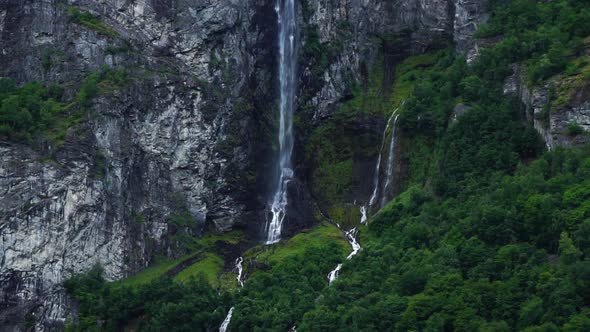 Norway landscape, big waterfall close up moving down the rocks with green forest below