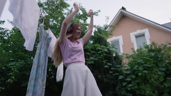 Joyful Happy Young Woman in Headphones Listening to Music Dancing in Slow Motion Outdoors