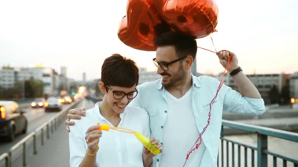 Romantic Young Couple Dating Outdoor and Blowing Bubbles