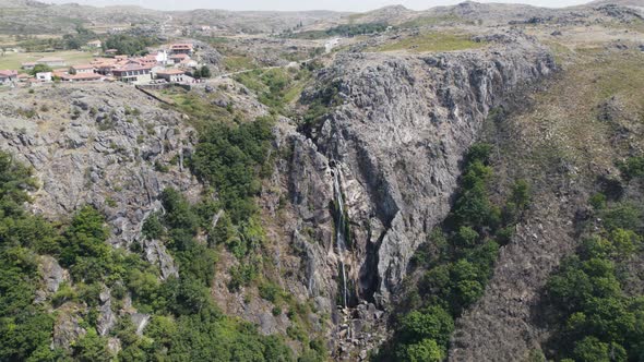 Picturesque village on top of the cliff with small waterfall cascading on rocky mountainside