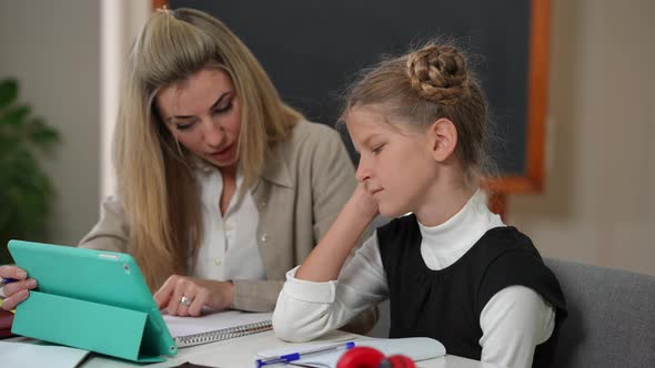 Side View Tired Teenage Girl Sitting with Teacher at Desk Talking