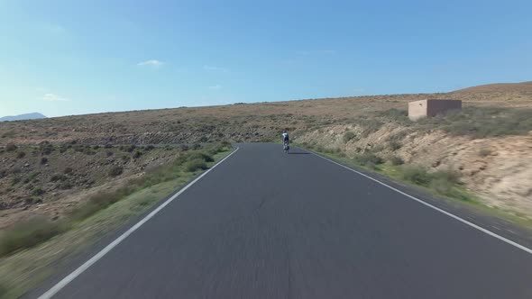 Aerial shot of a young athletic woman cycling on a road bike in the mountains in Spain. Shot at dayt