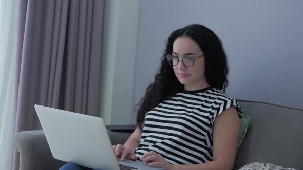 Woman Typing on Laptop Sitting on Sofa at Home, Businesswoman Sits at Home Types on Smartphone