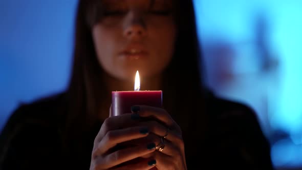 Young Pretty Witch Is Telling Fortune By Flame of Candle Closeup Portrait in Darkness