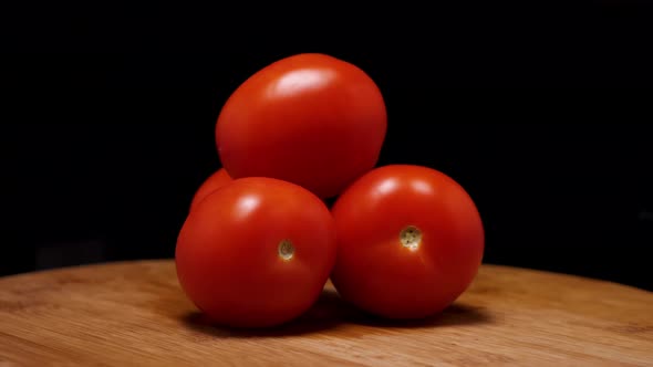 The camera flies around ripe red tomatoes on a wooden background. Parallax effect