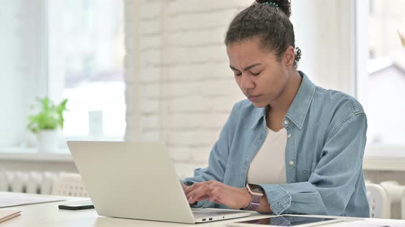 Young African Woman with Headache Working on Laptop