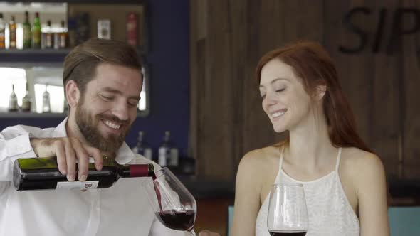 Slow motion shot of couple pouring red wine and clinking glasses