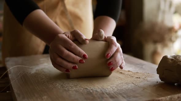 Close Up Footage of Female Hands with Beautiful Red Manicure Holding Clay and Kneading It on a