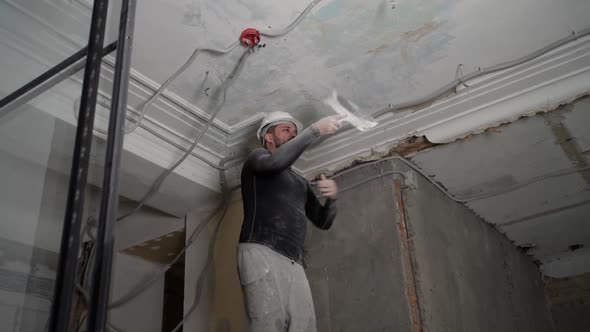 Fat Bearded Adult Man in Protective Helmet and Black Tight Fitting Clothing Remove Construction