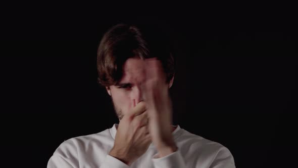 Trendy Young Man covering nose from stench, smelling gesture, close, black background