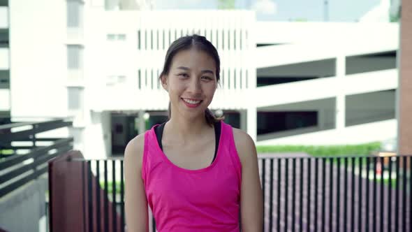 Young Asian woman feeling happy smiling and looking to camera after running on street in urban city