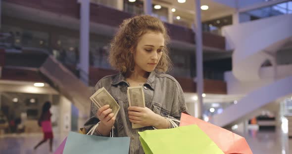 Pretty Young Girl Counting Money Standing in Shopping Mall